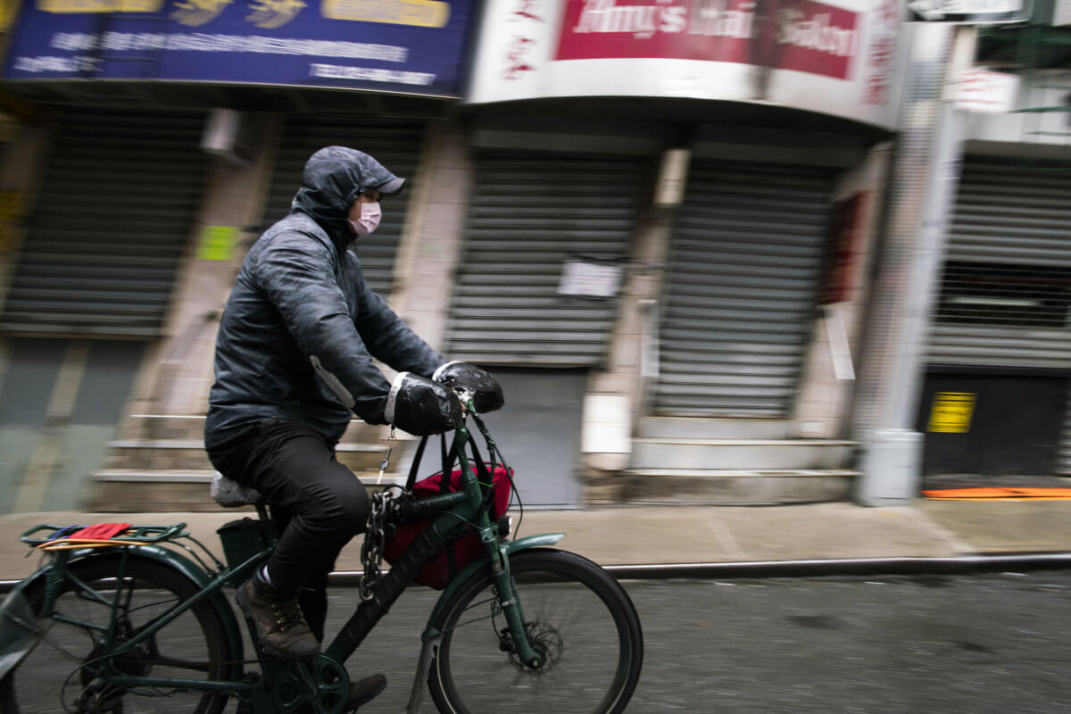 A food delivery worker wears a face mask as he rides his bicycle through Chinatown during the outbreak of coronavirus disease (COVID-19), in New York