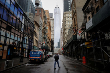 FILE PHOTO: A man crosses a nearly deserted Fulton Street in the financial district of lower Manhattan in New York