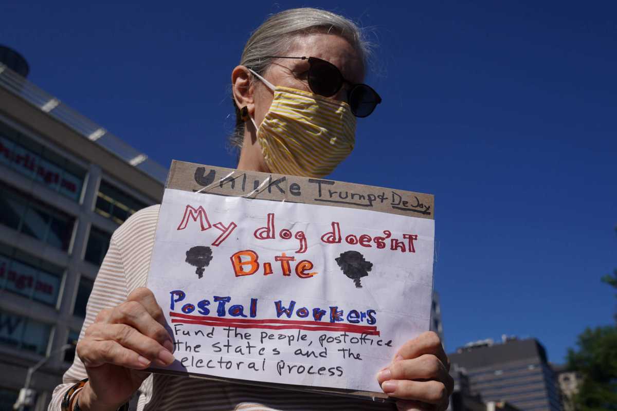 Woman holds a sign during a news conference about USPS in New York City