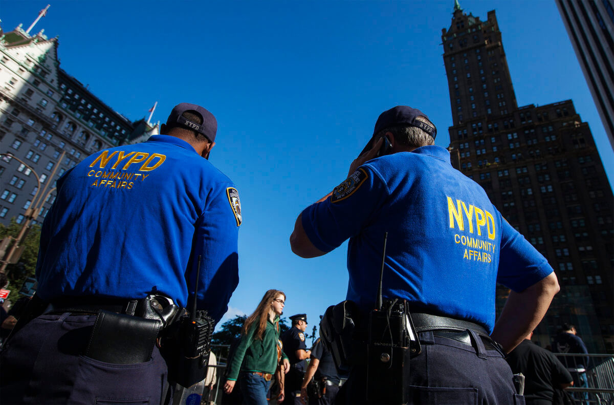 New York Police Department officers wait to register newly purchased iPhones outside of the Apple Store on 5th Avenue following the release of the Apple iPhone 5 phone in New York