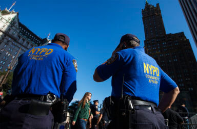 New York Police Department officers wait to register newly purchased iPhones outside of the Apple Store on 5th Avenue following the release of the Apple iPhone 5 phone in New York