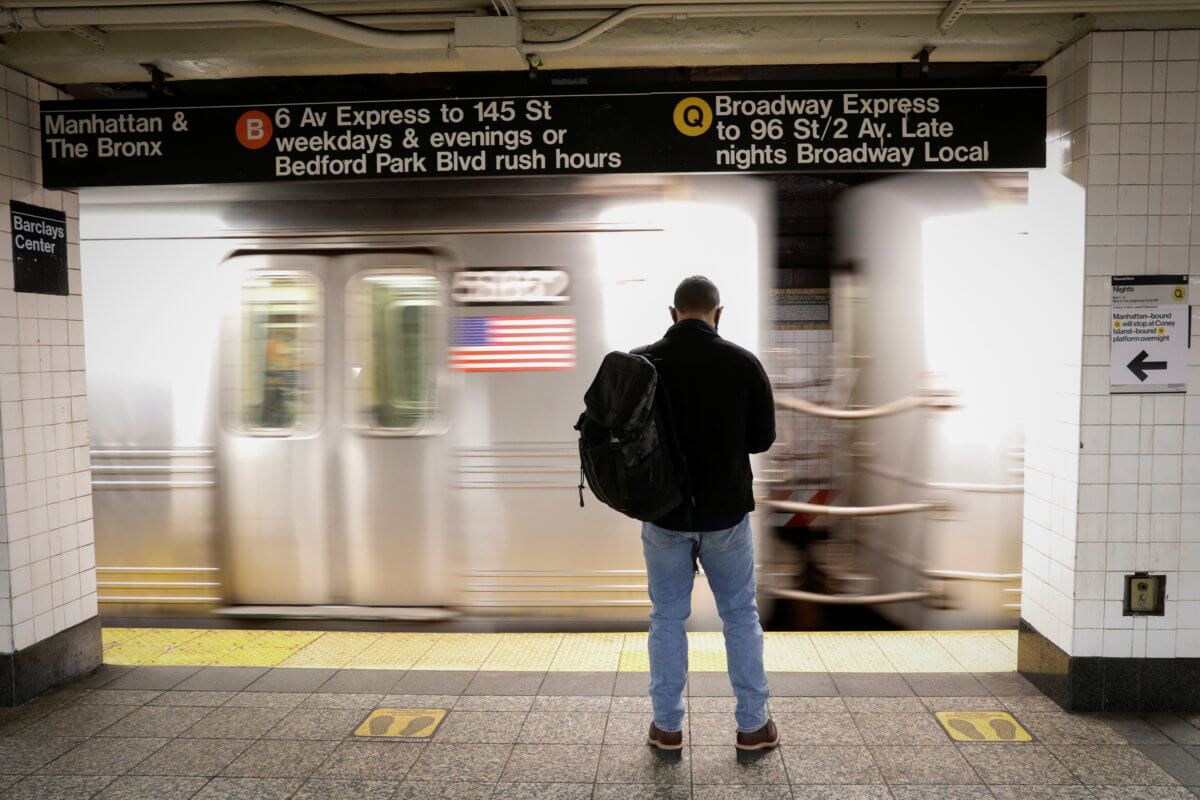 A passenger waits as a New York City subway train pulls into the station in Brooklyn, New York