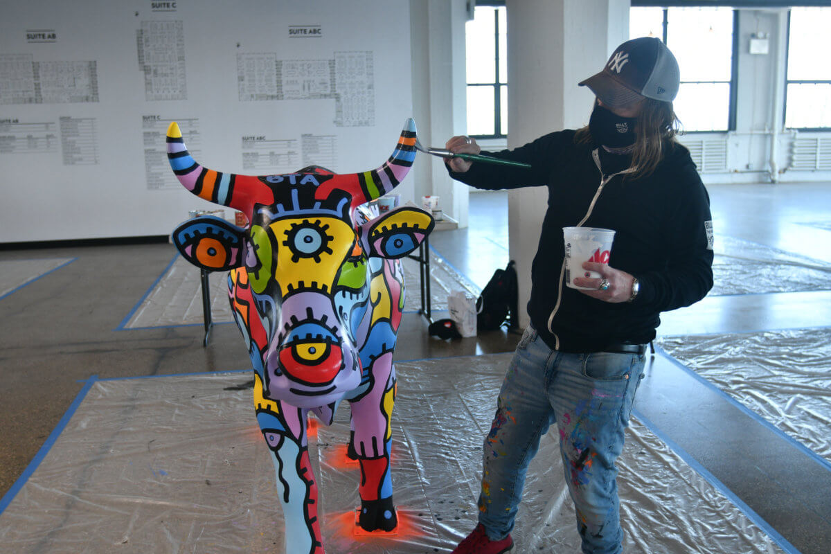 Billy the Artist paints a bull  before the cow parade.