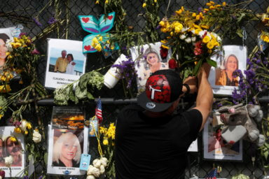 FILE PHOTO: A man places flowers on a makeshift memorial for the victims of the Surfside’s Champlain Towers South condominium collapse in Miami, Florida