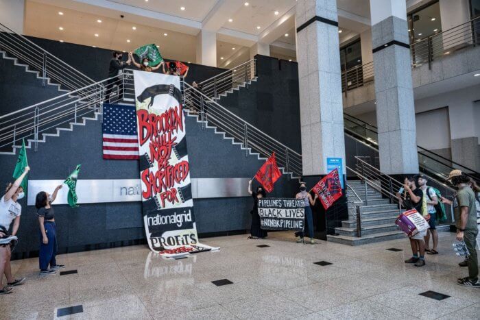 Protesters drop a banner at National Grid's downtown Brooklyn headquarters