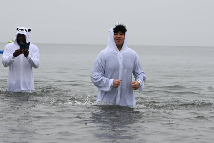 men stand in the ocean in polar bear suits at the coney island polar bear plunge