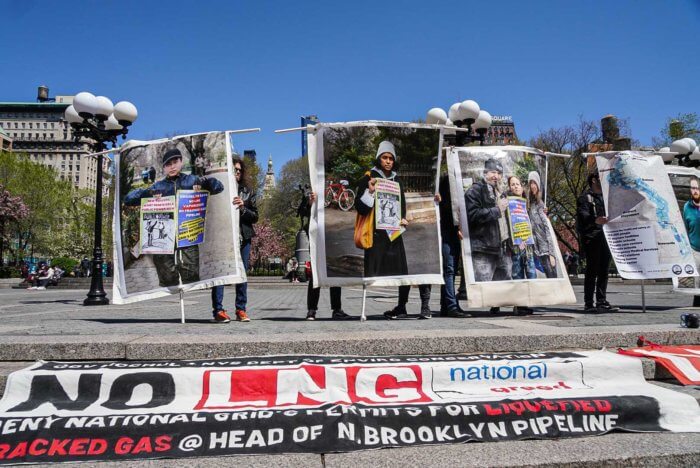 people hold signs and photos at climate utilities protest