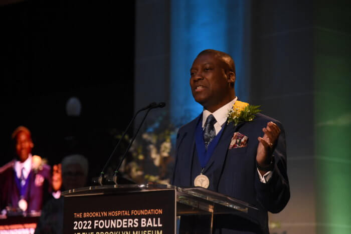 dr. louisdon pierre makes a speech at a podium after receiving a medal at the brooklyn hospital center's gala