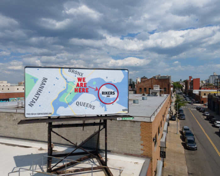 billboard in gowanus with a map with rikers island circled and "we are here" text