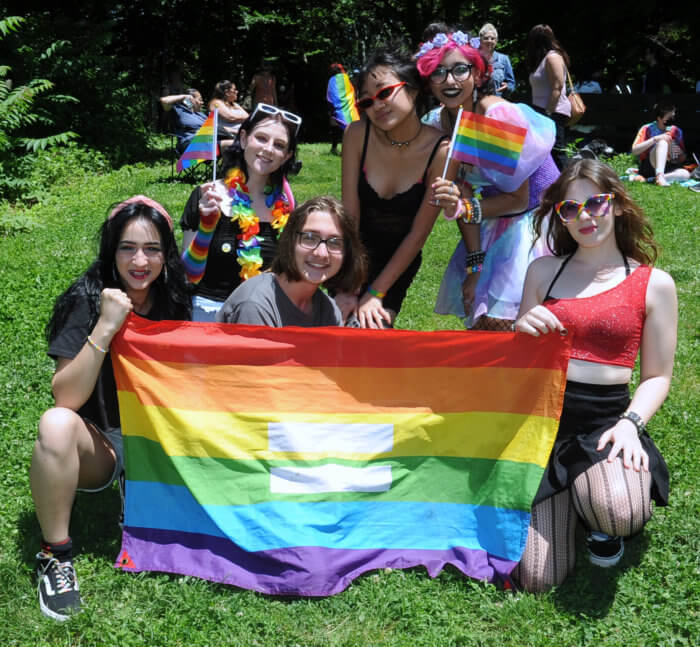 people pose with a rainbow flag on a lawn at gayridge pride