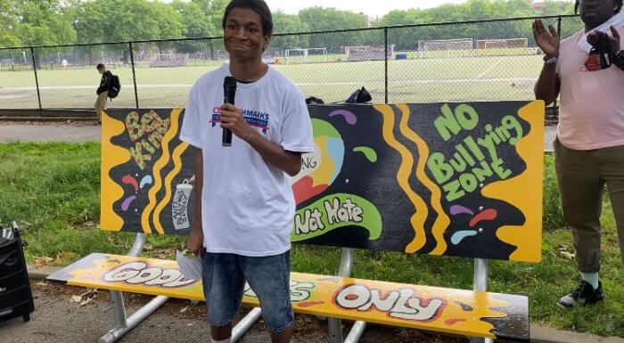 Student smiling as he talk about art project on benches