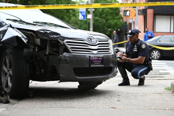 police look at crumpled car hood after motorcycle rider killed