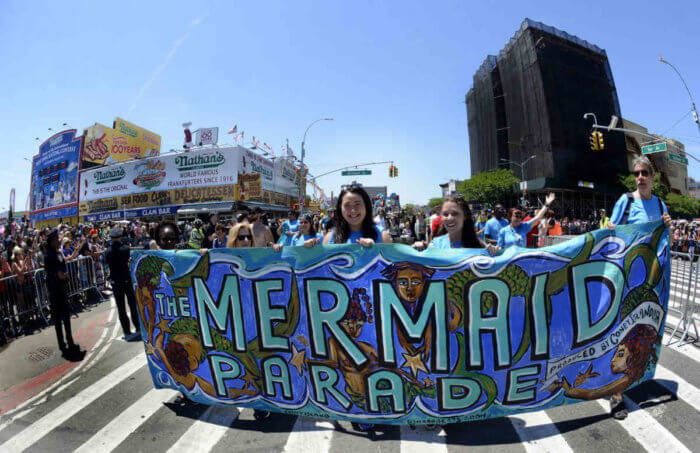people with colorful mermaid parade banner