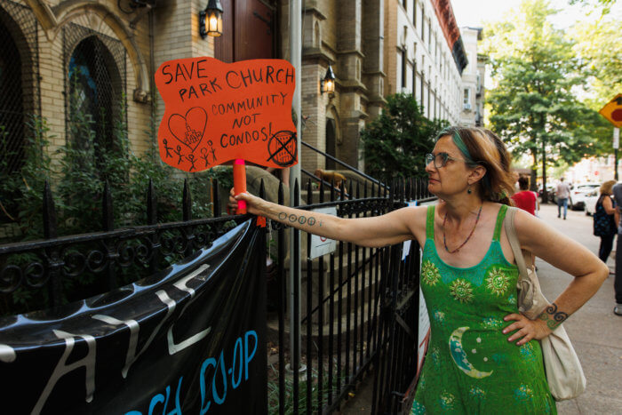 woman with orange sign outside church rally