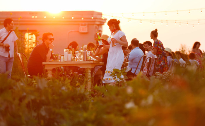 people sit around a large table on a rooftop at brooklyn grange's compost dinner