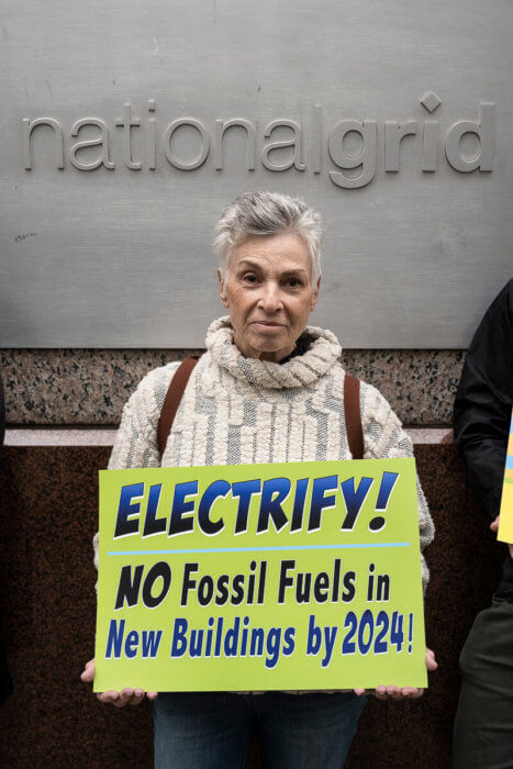 woman with short hair holding a sign for no fossil fuels climate action protest