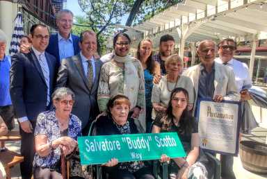 people with buddy scotto street sign