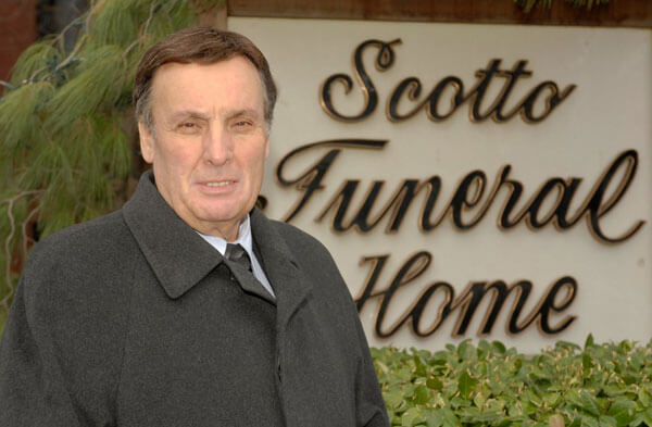 buddy scotto in front of sign