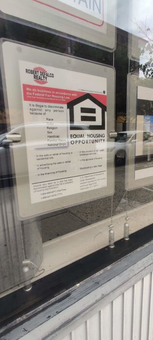 fair housing sign on window of defalco realty during voucher discrimination protest