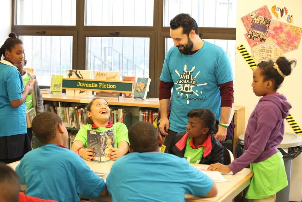Volunteers with I Will Graduate stand in classroom