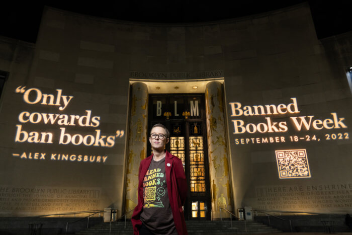 teacher standing outside brooklyn public library banned books week banner