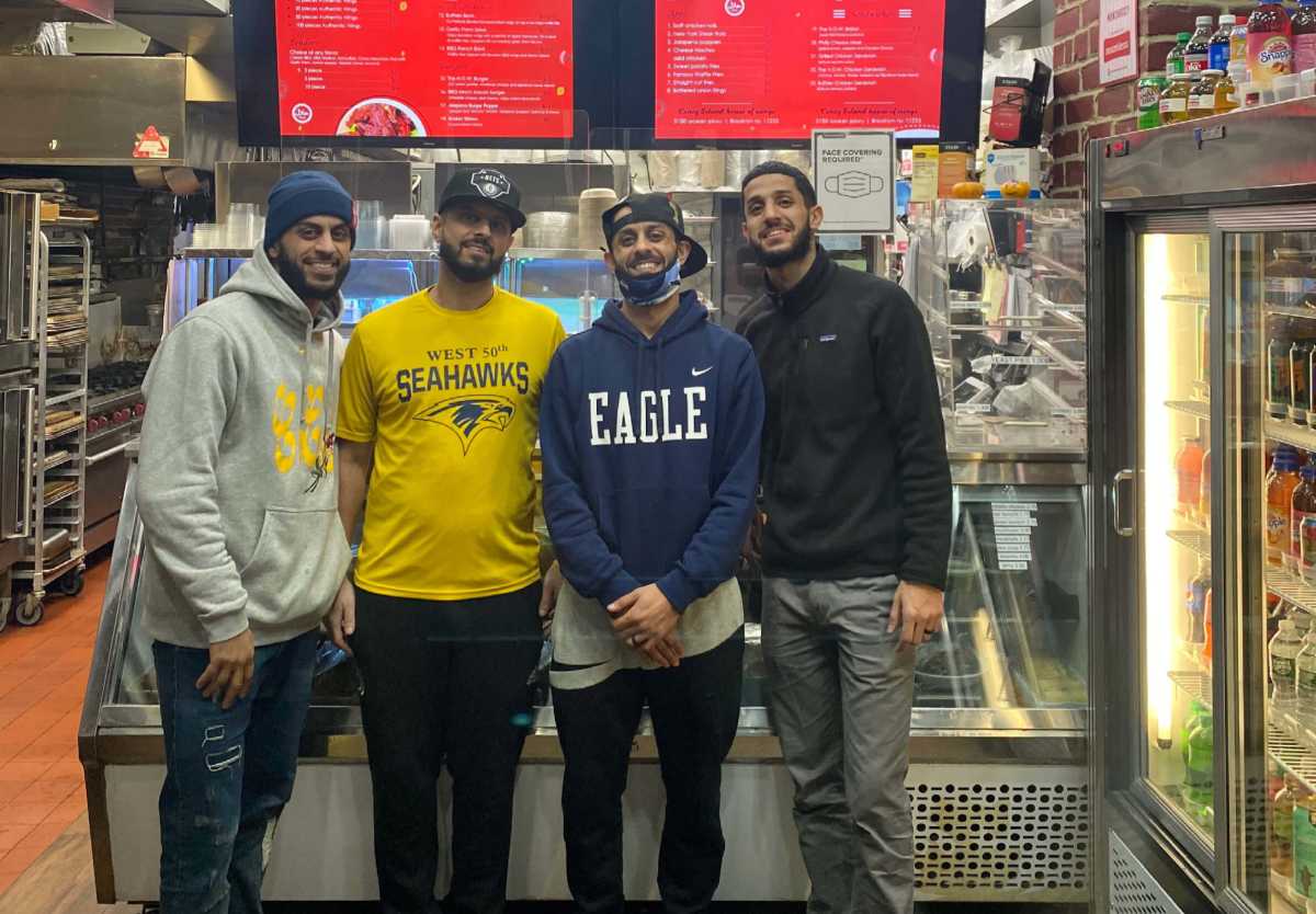 Business owners, Taha and Talal Alassari, stand with friends at their restaurant, Coney Island's House of Wings.