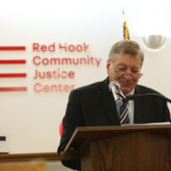 judge alex calabrese speaks in front of red hook community justice center sign