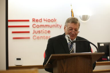 judge alex calabrese speaks in front of red hook community justice center sign