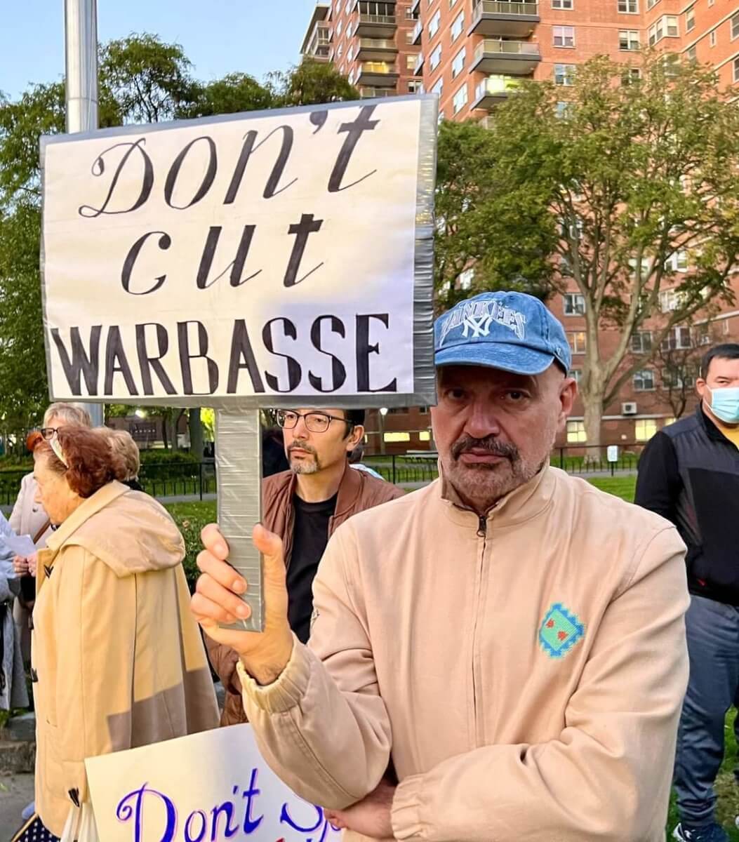 man holding warbasse houses sign