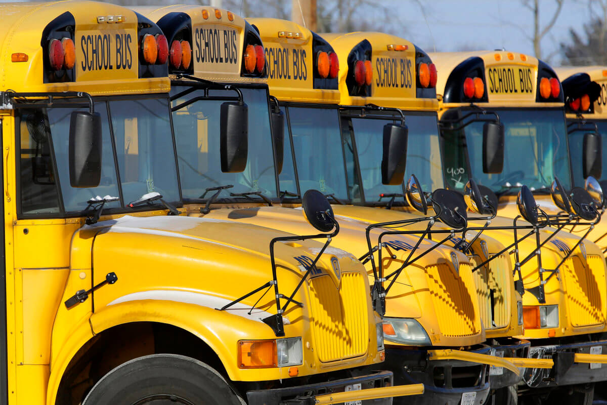 A row of DOE yellow school busses wait to pick up children.