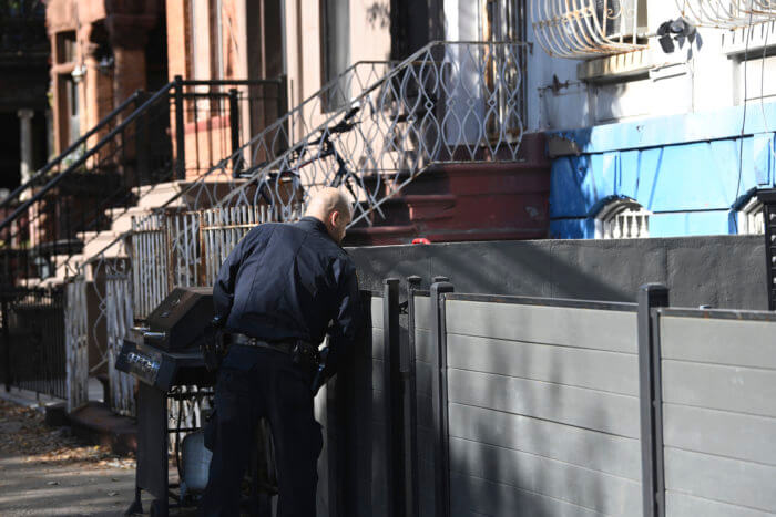 cop looks over wall in crown heights