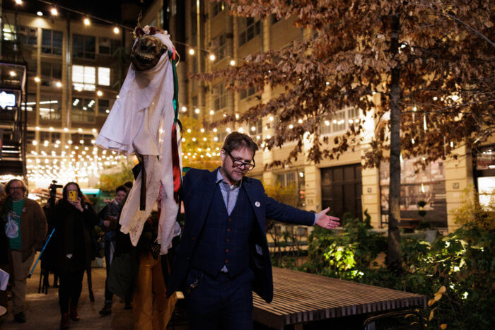 man carries horse head through courtyard in the mari lwyd