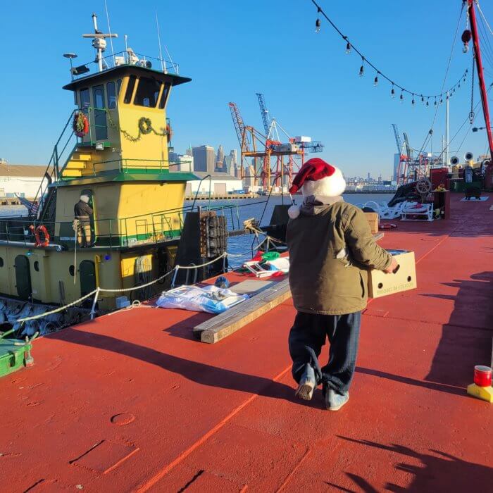man holding box on barge with santa hat on