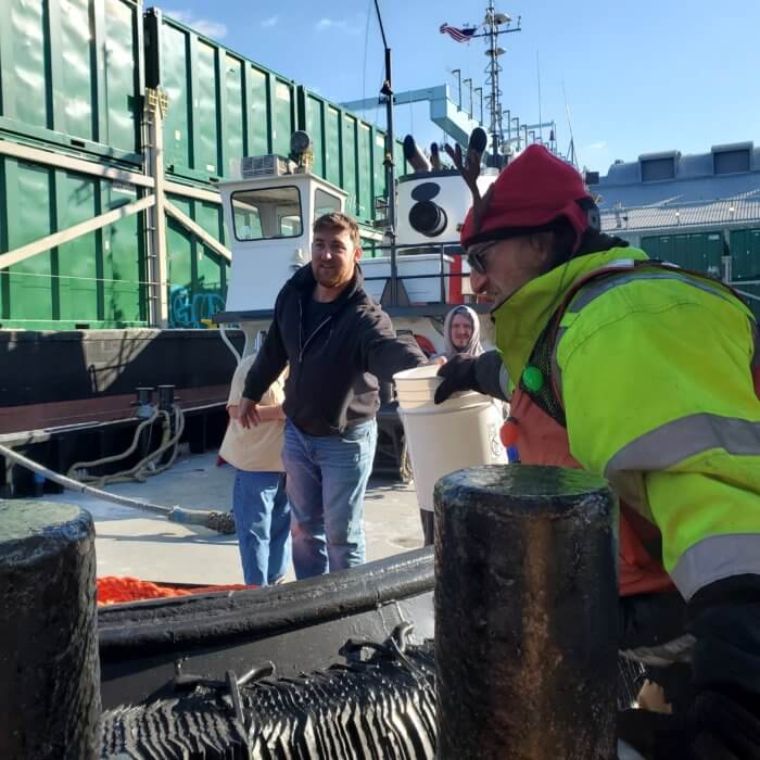 man handing bucket to mariner for operation christmas cheer