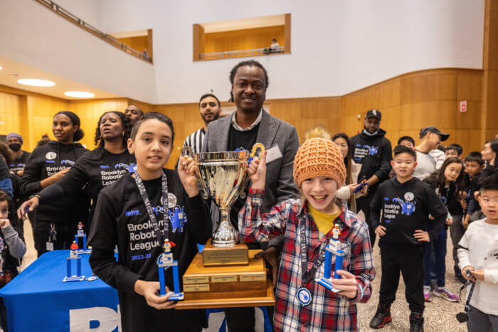 two winners of brooklyn public library robotics championship with trophy