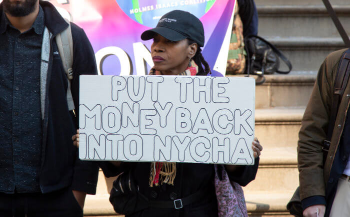 woman with fund NYCHA sign