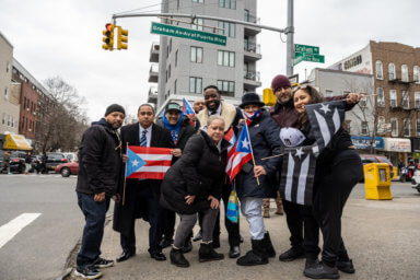 The local community poses outside the sign, and demands answers from the city and Mayor Eric Adams.