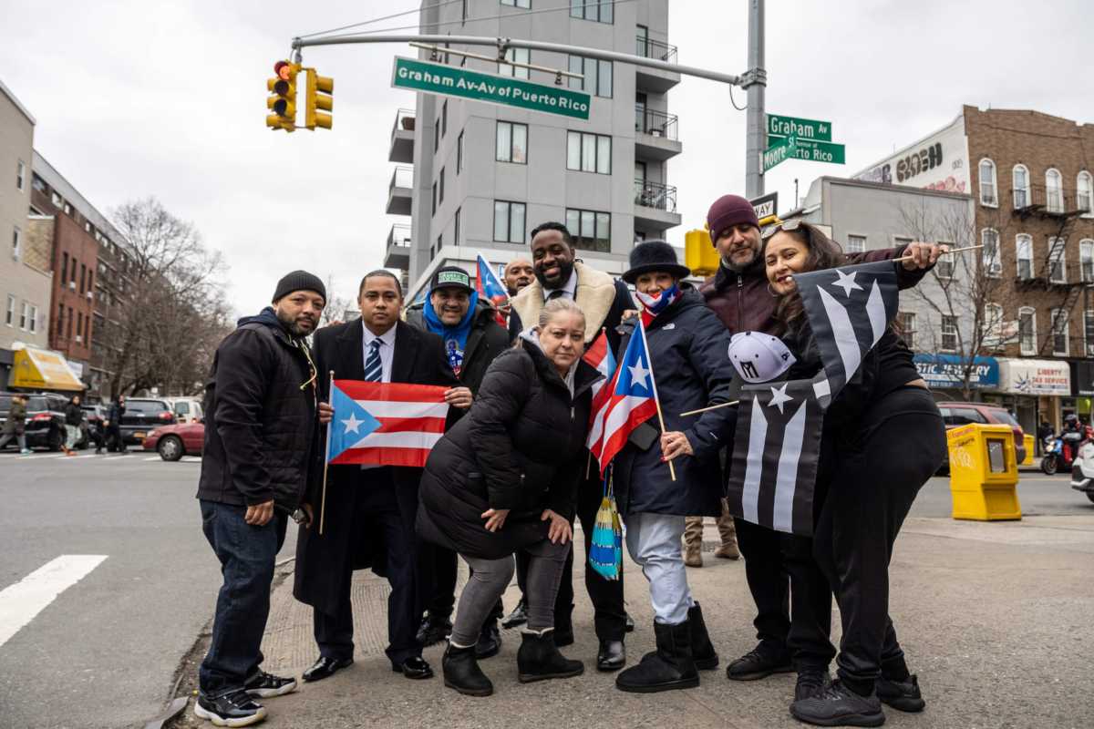 The local community poses outside the sign, and demands answers from the city and Mayor Eric Adams.