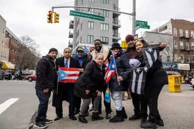 The local community poses outside the sign, and demands answers from the city and Mayor Eric Adams.