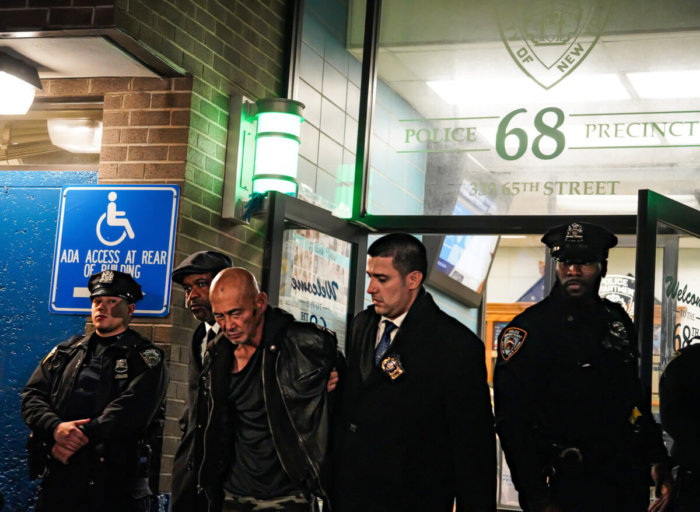 Sixty-two-year-old Weng Sor is led out of 68th precinct in cuffs.