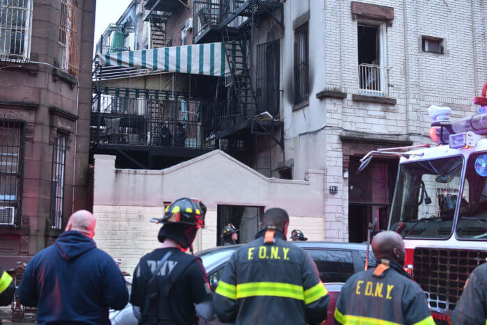 firefighters look up at building after residential fire