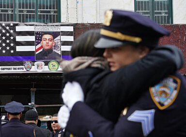 Officers embrace during a public funeral for Officer Adeed Fayaz.