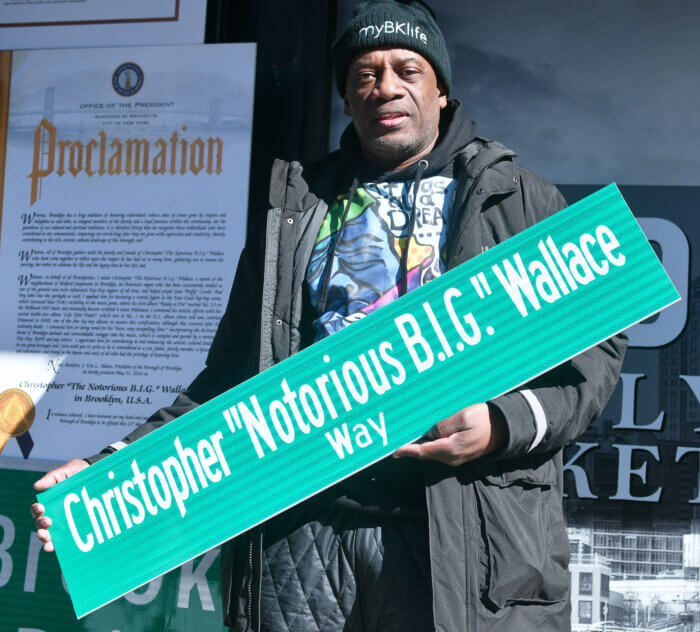 Leroy Mccarthy poses with a street sign honoring the legacy of Biggie Smalls on the 27th anniversary of Biggie's death.