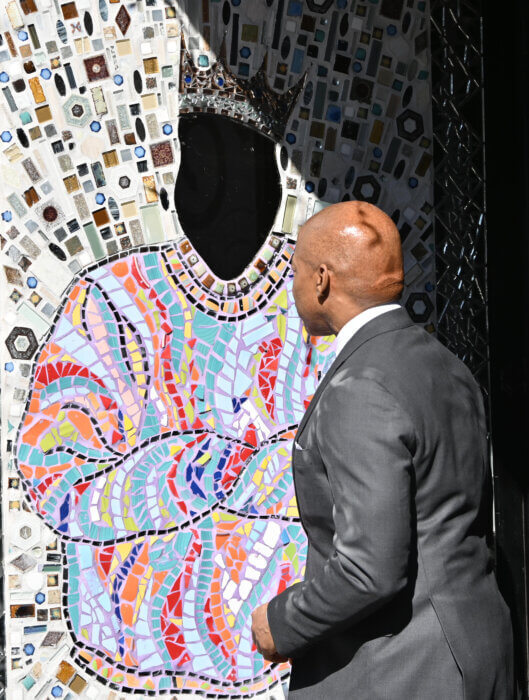 Mayor Eric Adams looks inside the mirror of a new Biggie Smalls mural at the intersection of Fulton Street and St. James Place.