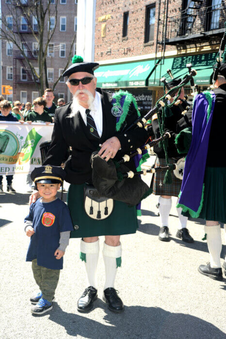 Bagpipe player and young child pose together during the 28th annual Bay Ridge St. Patrick's Day Parade