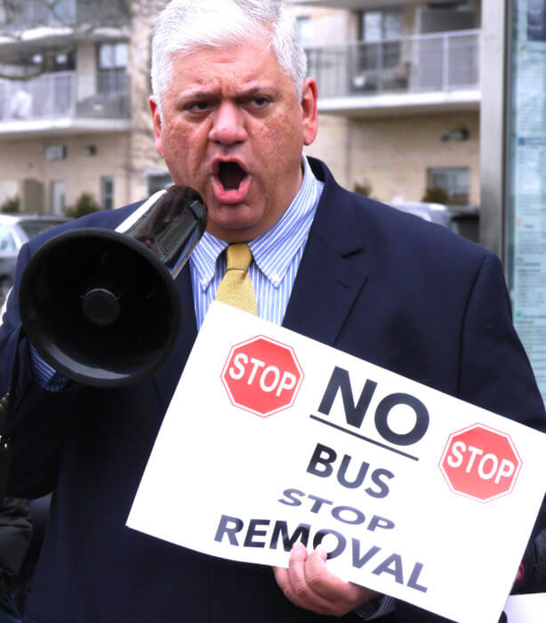 Brooklyn Conservative Party member Richard Barsamian holds a megaphone and sign at a protest against MTA bus changes.
