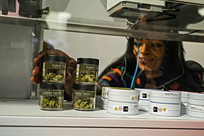 woman organizing marijuana on shelf in cannabis dispensary