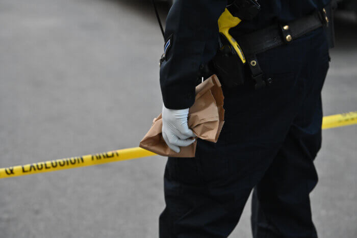 A cop from the 67th Police Precinct holds onto a handgun at the scene of the shooting in East Flatbush on April 24.