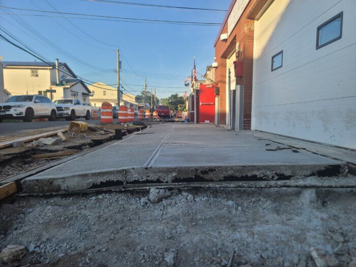 Image of damaged concrete and gaps beneath sidewalk outside the Gerritsen Beach fire department.