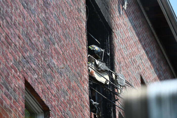 A firefighter tosses debris from a third floor apartment at 43 Street in Borough Park